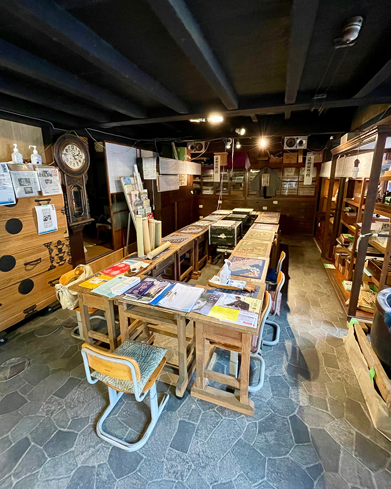 染色の展示コーナーと学校机の集会所の写真