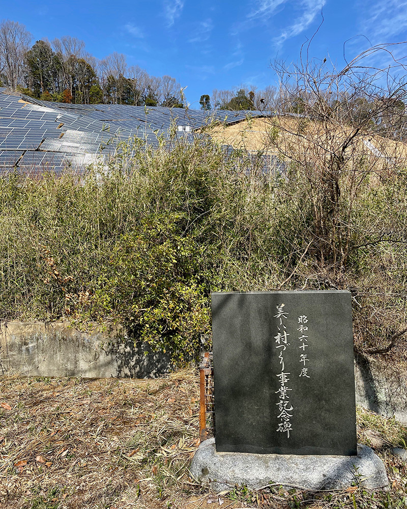 美しい村づくり事業記念碑の背後はメガソーラーの写真