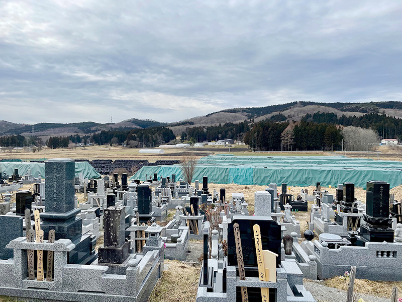 フレコンバッグの山を見つめるお墓たちの写真